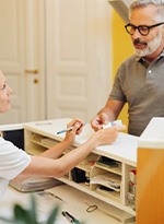 An older man using a credit card to pay for dental care