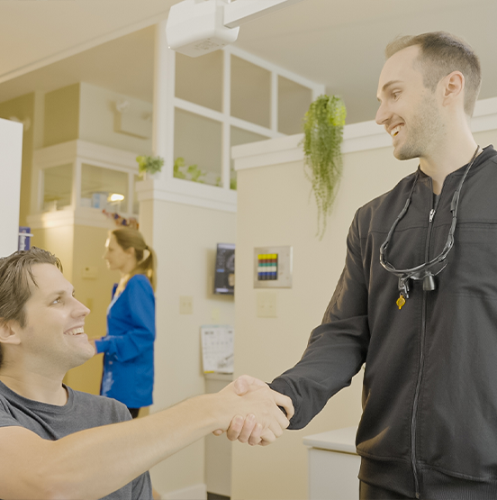 Smiling man shaking hands with his dentist