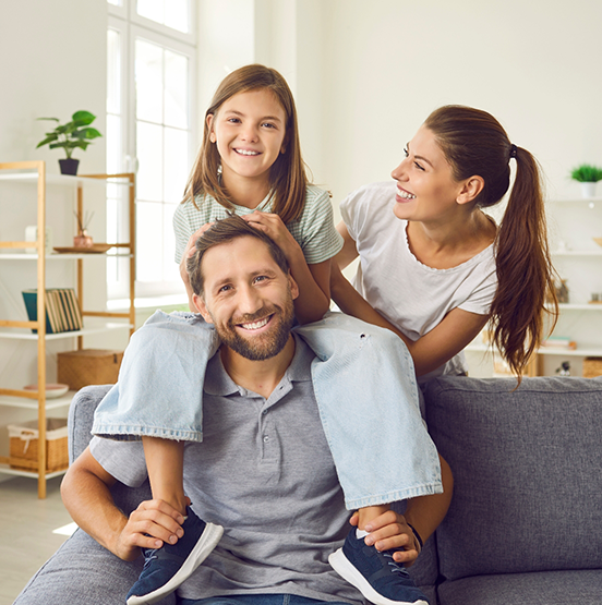 Family of three smiling in their living room