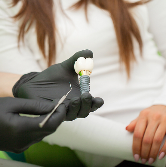 Dentist showing a model of a dental implant to a patient
