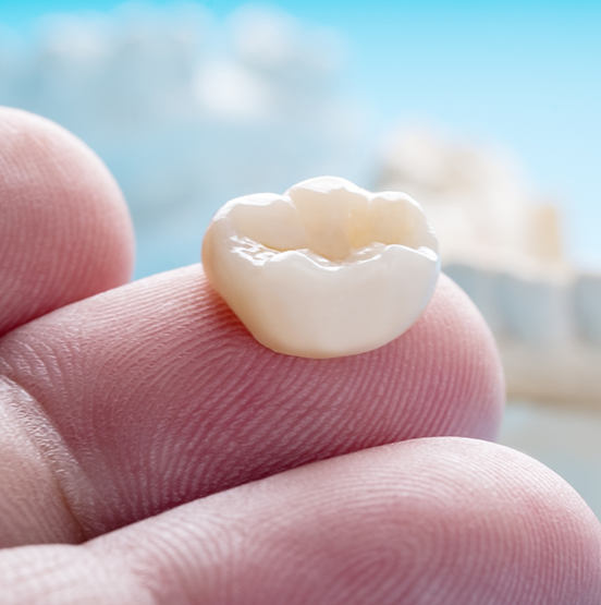 Dental crown resting on a person's finger