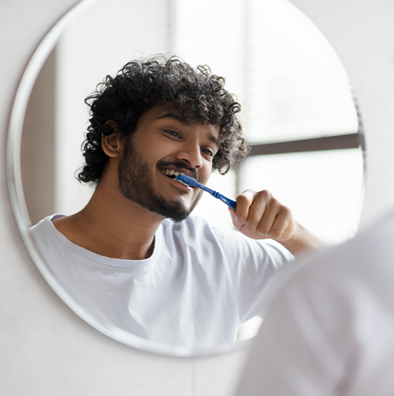 Young man brushing his teeth at home