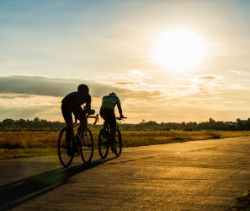 Two people riding their bikes in the sunset