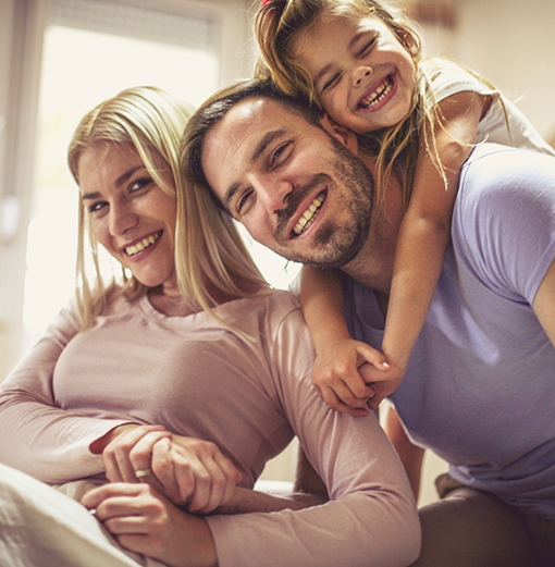 Family of three smiling after receiving dental services in Norwood