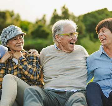 Three smiling seniors sitting in the grass