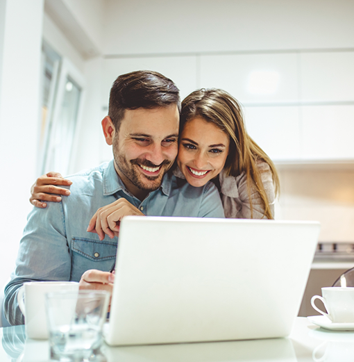 Man and woman smiling at a laptop together