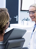 Smiling dentist talking to patient in treatment chair