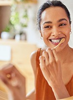 Woman smiling while brushing her teeth