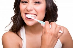 woman brushing her teeth smiling